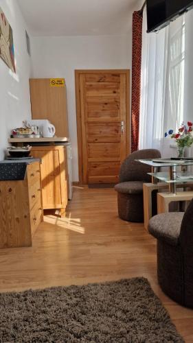 a living room with wooden floors and a kitchen with a table at Pokój od strony ulicy Kajki in Mikołajki