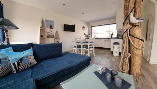 a living room with a blue couch and a kitchen at Vakantiehuis de Ankerplaats in Kamperland