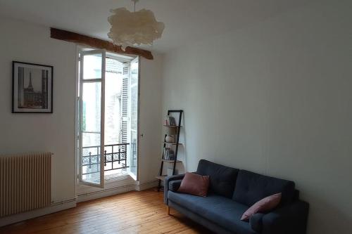 uma sala de estar com um sofá azul e uma janela em Rochereau de la Clautre em Périgueux