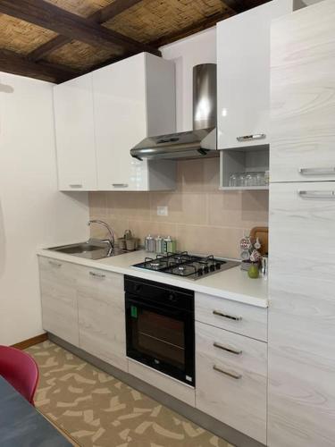 cocina con armarios blancos y fogones en Appartamento da Patrizia, en Simaxis