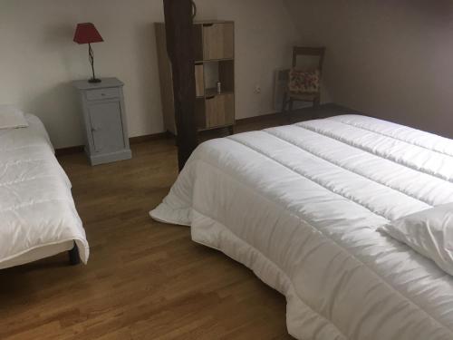 ein Schlafzimmer mit einem großen weißen Bett und einem Stuhl in der Unterkunft LES GABARES in Gohier