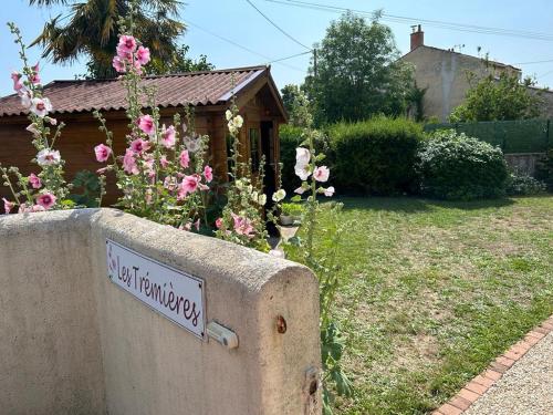 a sign on a wall in a yard with flowers at Les Trémières in Le Thou