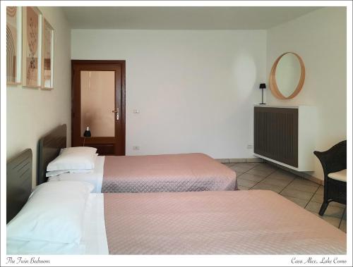 um quarto de hotel com duas camas e um espelho em Azalea di Gigliola Ziello - "Casa Alice" em Cremia