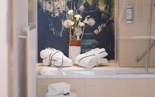 a bathroom with towels and a vase of flowers on a counter at Suite Hotel Leipzig in Leipzig