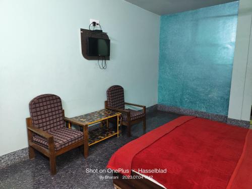 two chairs and a tv in a room with a red carpet at Hotel Swapna in Vānivilāsa Puram