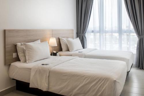 two beds in a hotel room next to a window at The Signature Serviced Suites Puchong in Puchong