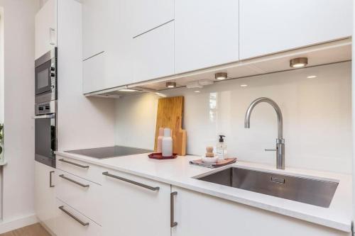 a kitchen with white cabinets and a sink at Strøken loftleilighet midt i Oslo. in Oslo