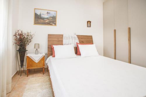 a white bedroom with a bed and a side table at Froso's Home in Zaros