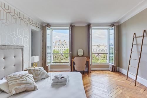 een slaapkamer met een wit bed en grote ramen bij Apartment Bastille by Studio prestige in Parijs