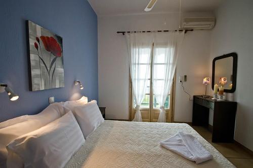 Violetta Apartments في نيو كليما: غرفة نوم بسرير وملاءات بيضاء ونافذة