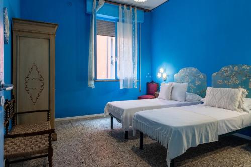 Habitación azul con 2 camas y ventana en Un tocco di Blu - La Vegra Apartment en Ferrara