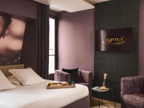 a hotel room with a bed and two chairs at Legend Hôtel Paris in Paris