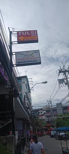 a man walking down a city street with a sign at Tulsi Inn at Walking Street in Pattaya South