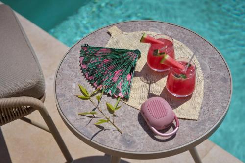 a glass table with two drinks and a ball and an umbrella at Once in Mykonos - Designed for Adults in Ornos