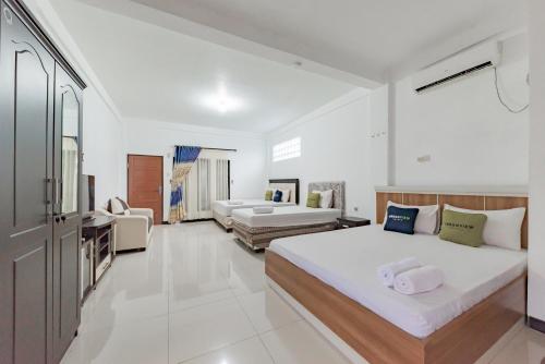 a bedroom with two beds and a living room at Urbanview Hotel 99 Syariah Banjarbaru by RedDoorz in Martapura
