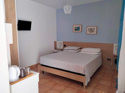 a bedroom with a white bed and a television at B&B Masseria Liberatore in Mattinata