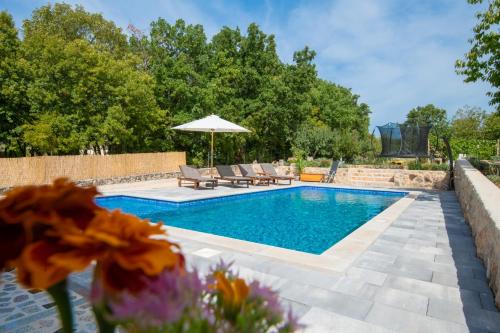 a pool with chairs and an umbrella and some flowers at Holiday House Tone, Imotski-Drum-Makarska in Drum