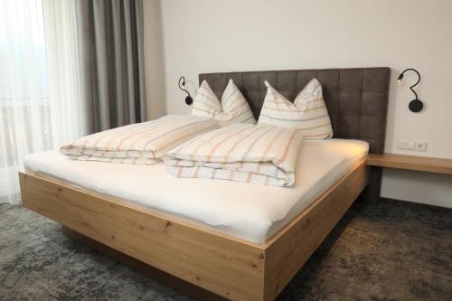 a bed with a wooden frame and pillows on it at Frühstückspension Jagdhof in Obertilliach