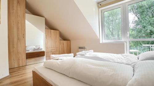 a white bedroom with two beds and a window at Apartamenty Sun & Snow Morskie Oko in Międzyzdroje