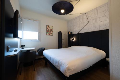 a bedroom with a white bed and a desk and a window at ibis Perpignan Sud Saint Charles in Perpignan