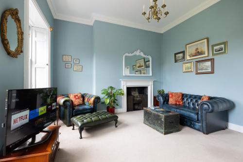 a living room with blue walls and couches and a tv at Crescent Green in Bath