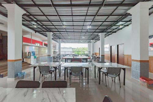 - Zona de comedor con mesas y sillas en un edificio en Urbanview Hotel 99 Syariah Banjarbaru by RedDoorz, en Martapura