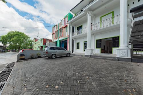 a car parked in a parking lot next to a building at Urbanview Hotel 99 Syariah Banjarbaru by RedDoorz in Martapura
