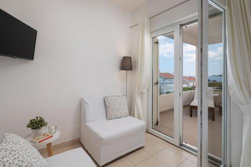 ein Wohnzimmer mit einem weißen Stuhl und einem Balkon in der Unterkunft Apartment Tihi in Vodice