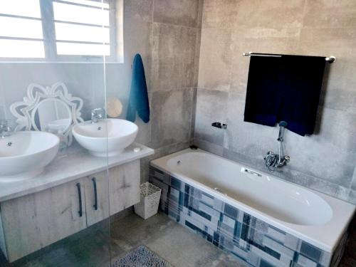 a bathroom with two sinks and a bath tub and a mirror at Pêrel of Perlemoenbaai in Gansbaai
