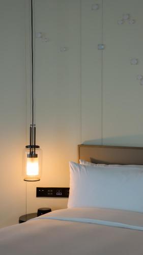 a bed with a white pillow and a light at Yancheng Marriott Hotel in Yancheng