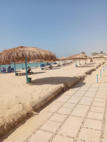 a beach with straw umbrellas and people on it at شاليه فندقي ڤيو البحر Ain sokhna-families& married only in Ain Sokhna