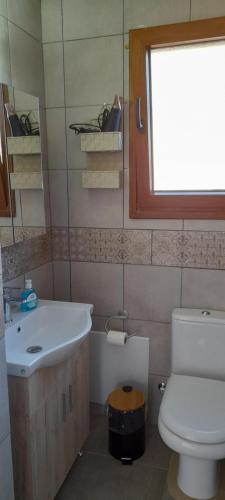 a bathroom with a sink and a toilet and a window at 4 Season Cozy Home in Samothráki