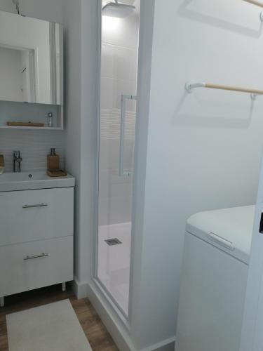 uma casa de banho branca com um chuveiro e um lavatório. em Coeur de ville Appartement t3 pour 6 personnes N1 7 em La Grande-Motte
