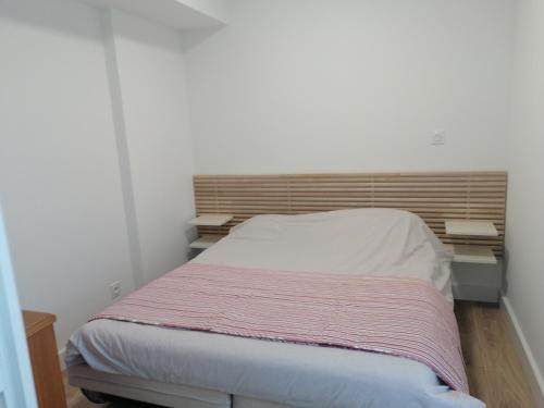 um pequeno quarto com uma cama e uma cabeceira em madeira em Coeur de ville Appartement t3 pour 6 personnes N1 7 em La Grande-Motte