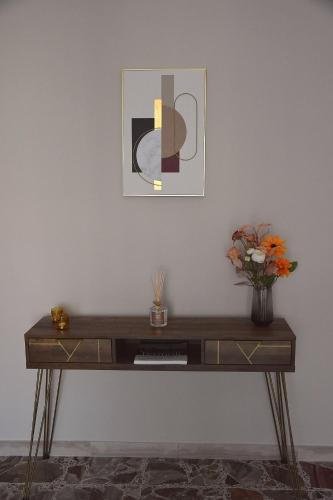 a desk with a vase of flowers and a picture at Russo Apartment in Termoli
