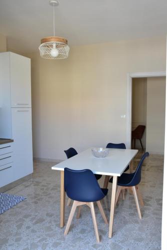 a dining room table with blue chairs and a kitchen at Russo Apartment in Termoli
