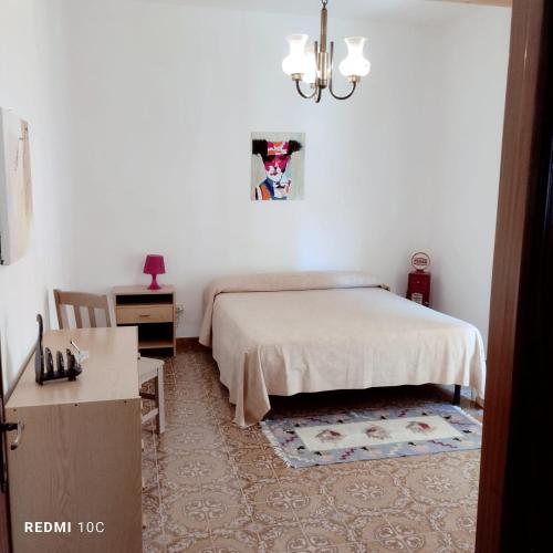蒙泰內羅迪比薩恰的住宿－La casina delle coste，一间卧室配有一张床、一张桌子和一个吊灯。