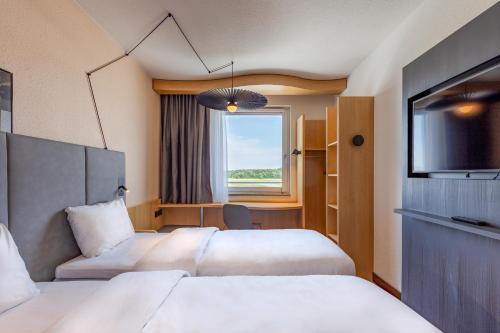 una camera d'albergo con due letti e una televisione di ibis Hotel Friedrichshafen Airport Messe a Friedrichshafen