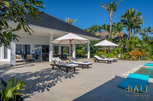 un patio con sillas y sombrillas y una piscina en Villa Akasa Segara Beachfront and Private Pool, en Banjar