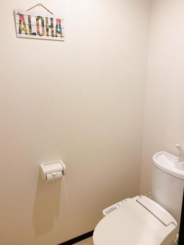 a bathroom with a toilet and a sign on the wall at KOHALA　HOTEL in Naha