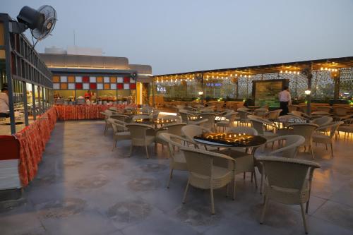 ein Restaurant mit Tischen und Stühlen auf einer Terrasse in der Unterkunft Hotel Haris MG Road Gurugram in Gurgaon