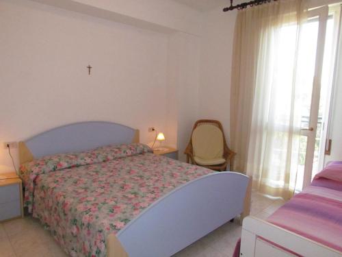 een slaapkamer met een bed, een stoel en een raam bij Appartamento Xibana in Bibione