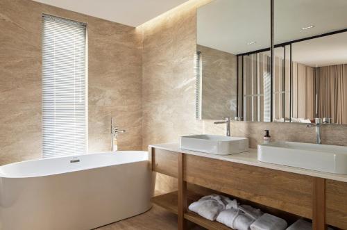 een badkamer met 2 wastafels, een bad en een spiegel bij Sol Tropikal Durrës in Durrës