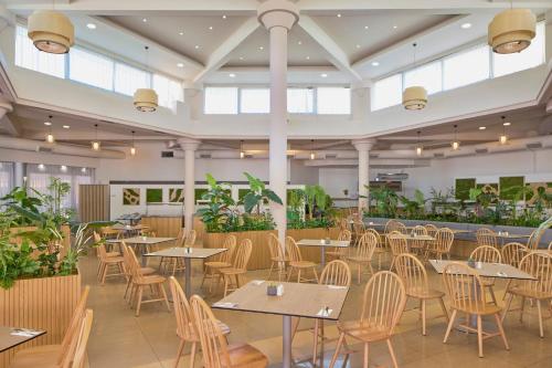 a restaurant with tables and chairs and plants at Sol Tropikal Durrës in Durrës