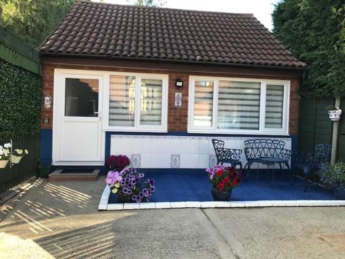 una pequeña casa con un banco y flores delante en Dolly Cottage Colchester, en Mile End