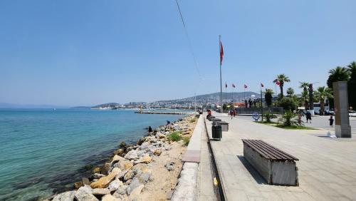 a sidewalk next to the water with a bench at Traumhaus mitten in der City 60 Meter zum Meer in Kuşadası