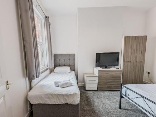 a small bedroom with two beds and a tv at Bentley House - By Sigma Stays in Crewe