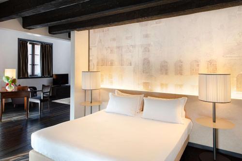a bedroom with a large white bed with two lamps at Hyatt Centric Murano Venice in Murano