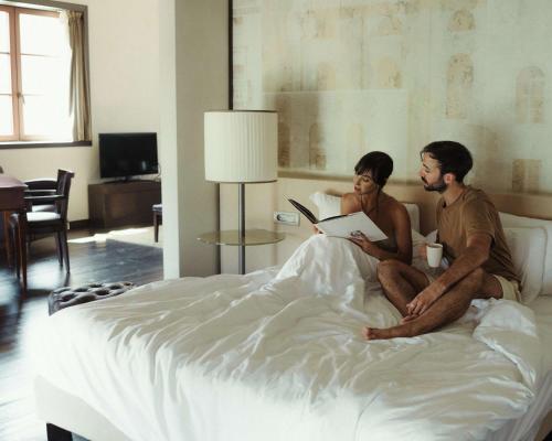 a man and woman sitting on a bed reading at Hyatt Centric Murano Venice in Murano