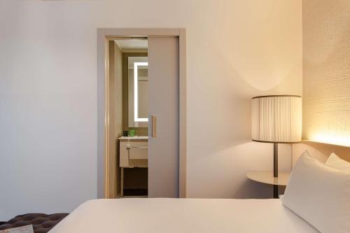 a bedroom with a white bed and a lamp at Hyatt Centric Murano Venice in Murano